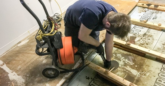 Man vacuuming flood water from floor